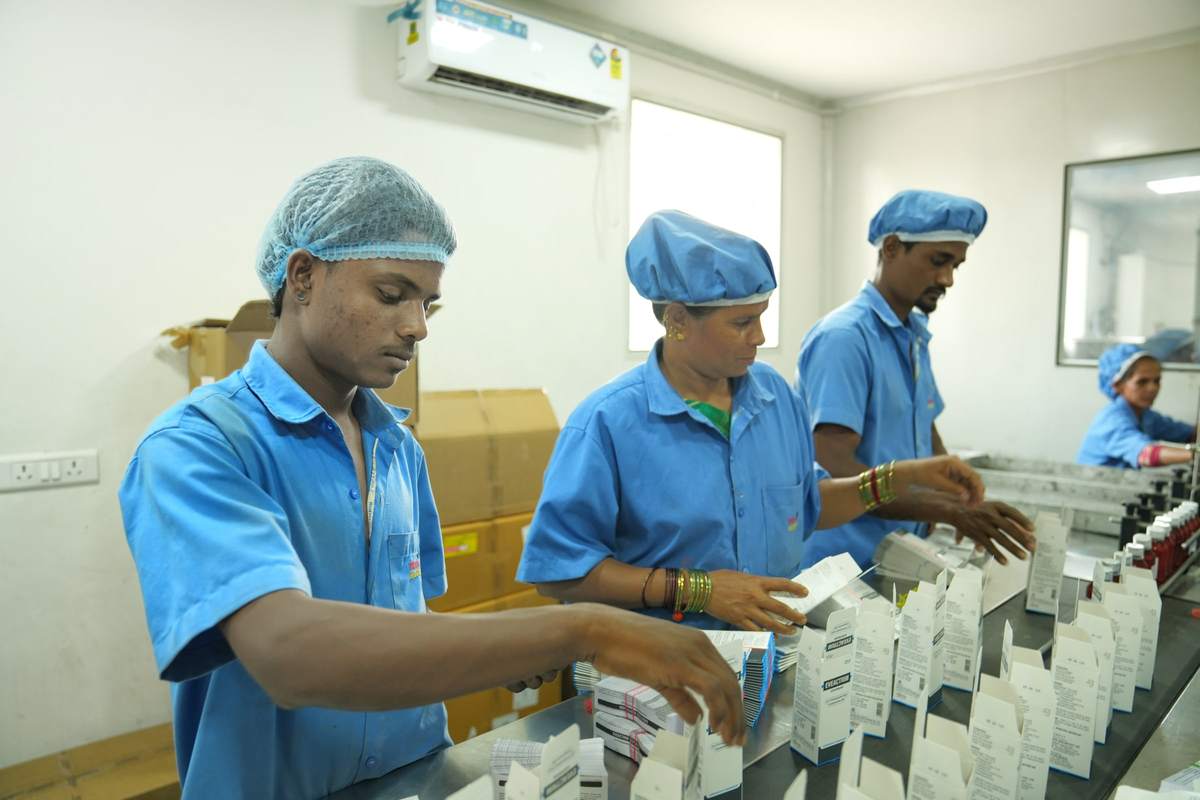 Packing staff placing bottles into printed cartons at a packing table