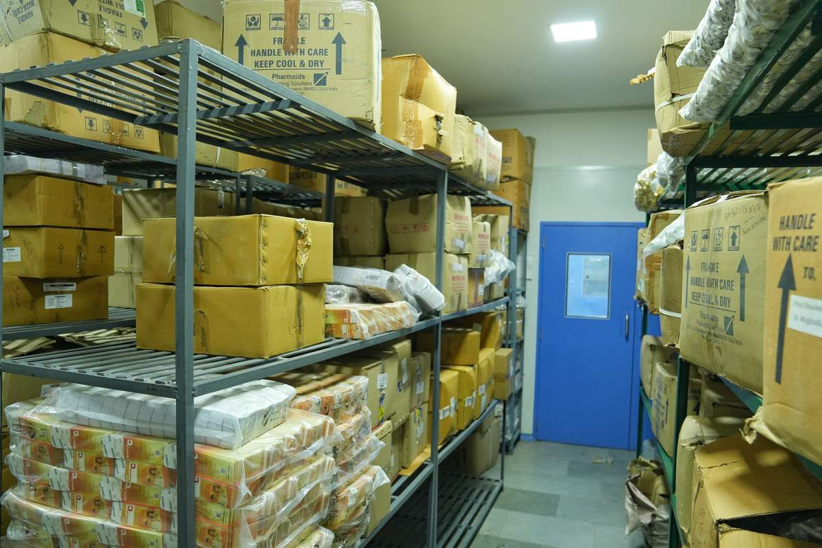 Storage room with steel racks holding labelled cartons and packing material